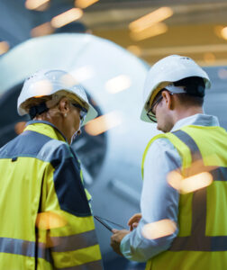 two industrial workers in hard hates reviewing plans