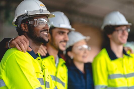 team of industrial workers in safety yellow jackets and white hard hats