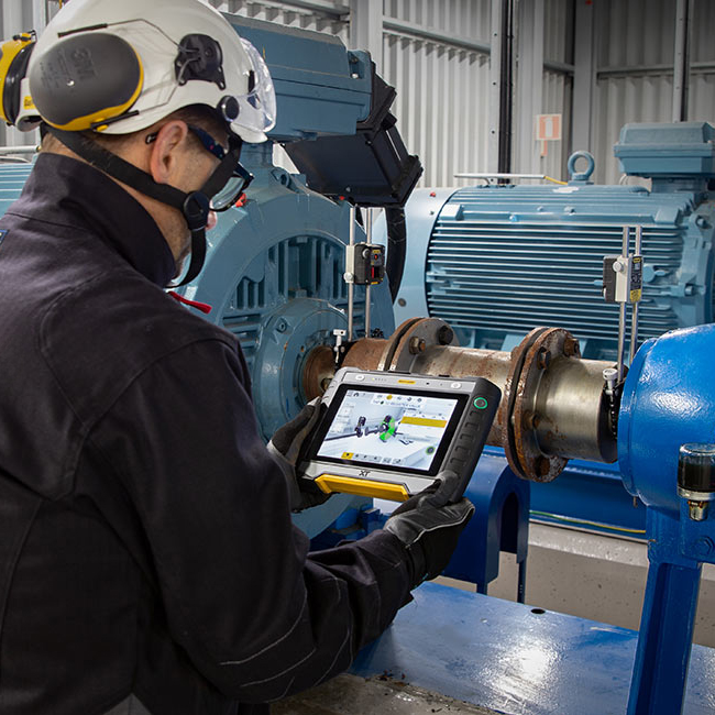 Industrial worker using laser alignment tool to align heavy machinery shaft